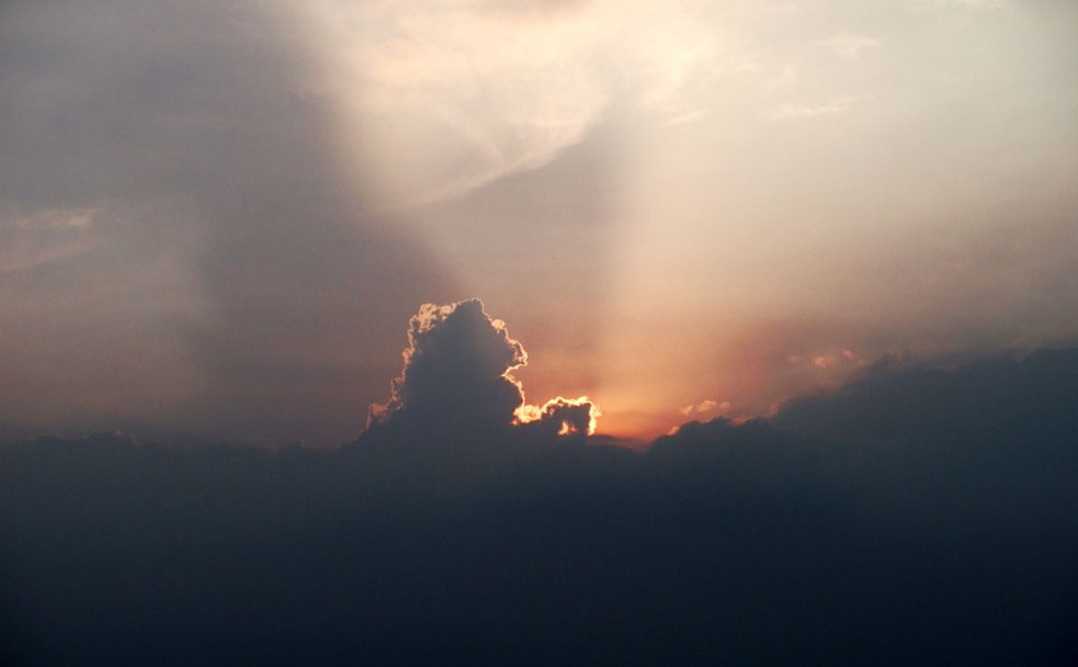 sun rays throws light from behind clouds which is shaped like a horse.